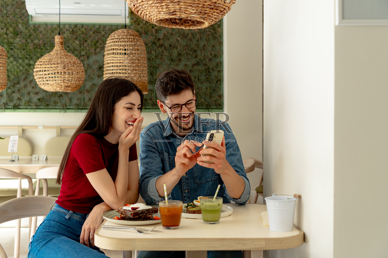 一对情侣在现代餐厅里欢笑并使用智能手机照片摄影图片