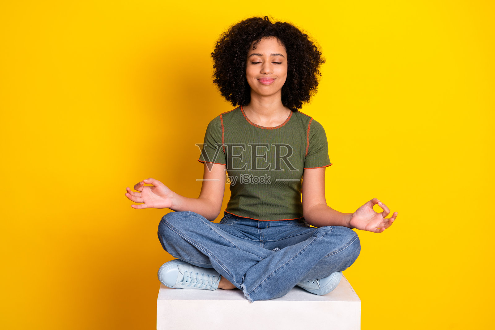 放松的年轻女性在明亮的黄色背景上以优雅的姿势冥想,休闲而时尚照片摄影图片