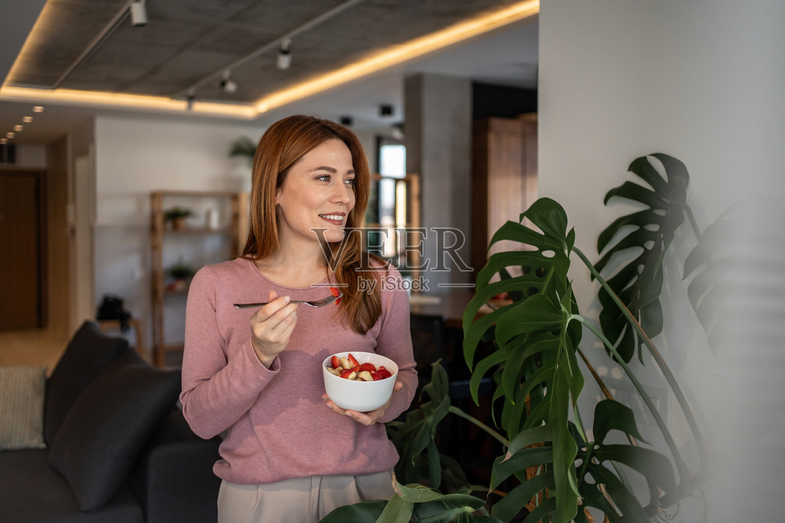 快乐的女人在家享用新鲜的水果沙拉照片摄影图片