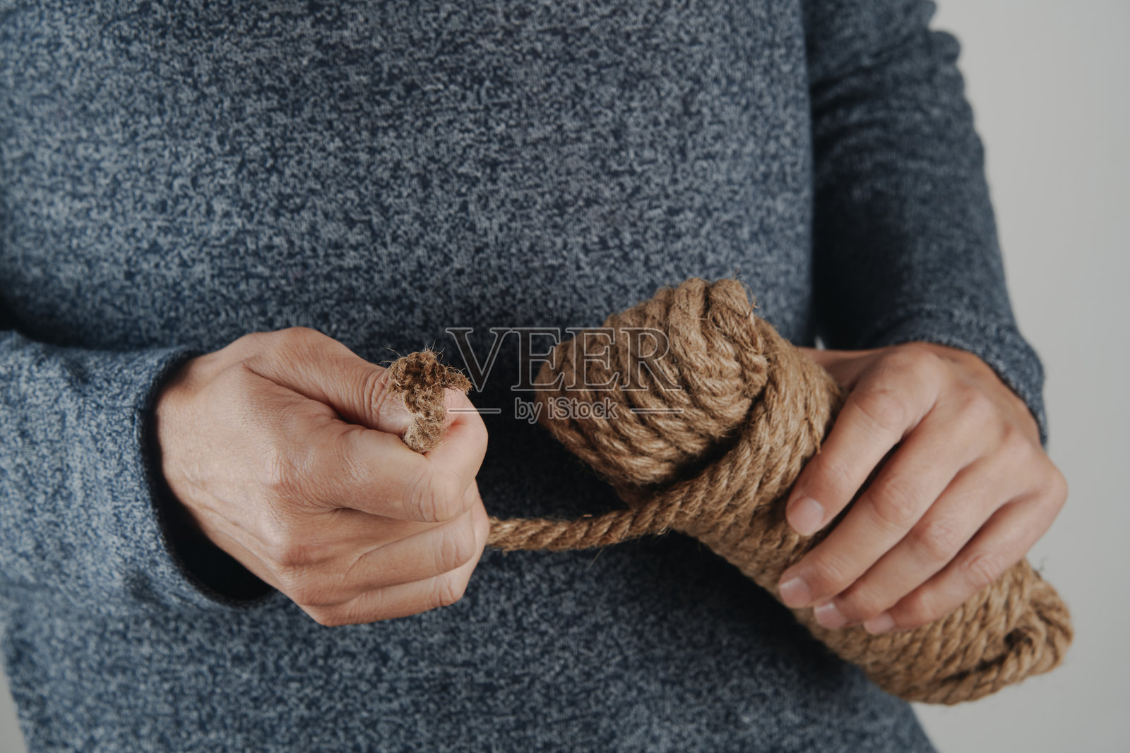 男人从缠绕的绳圈中拉出绳子照片摄影图片