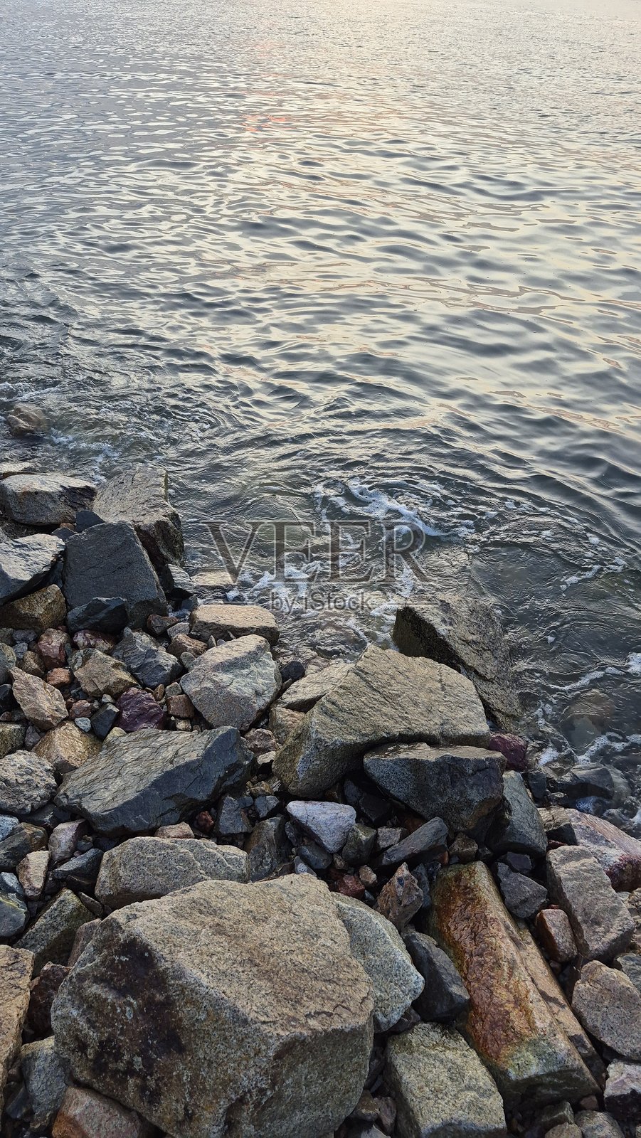 下午平静的海浪轻轻拍打着岸边的岩石照片摄影图片