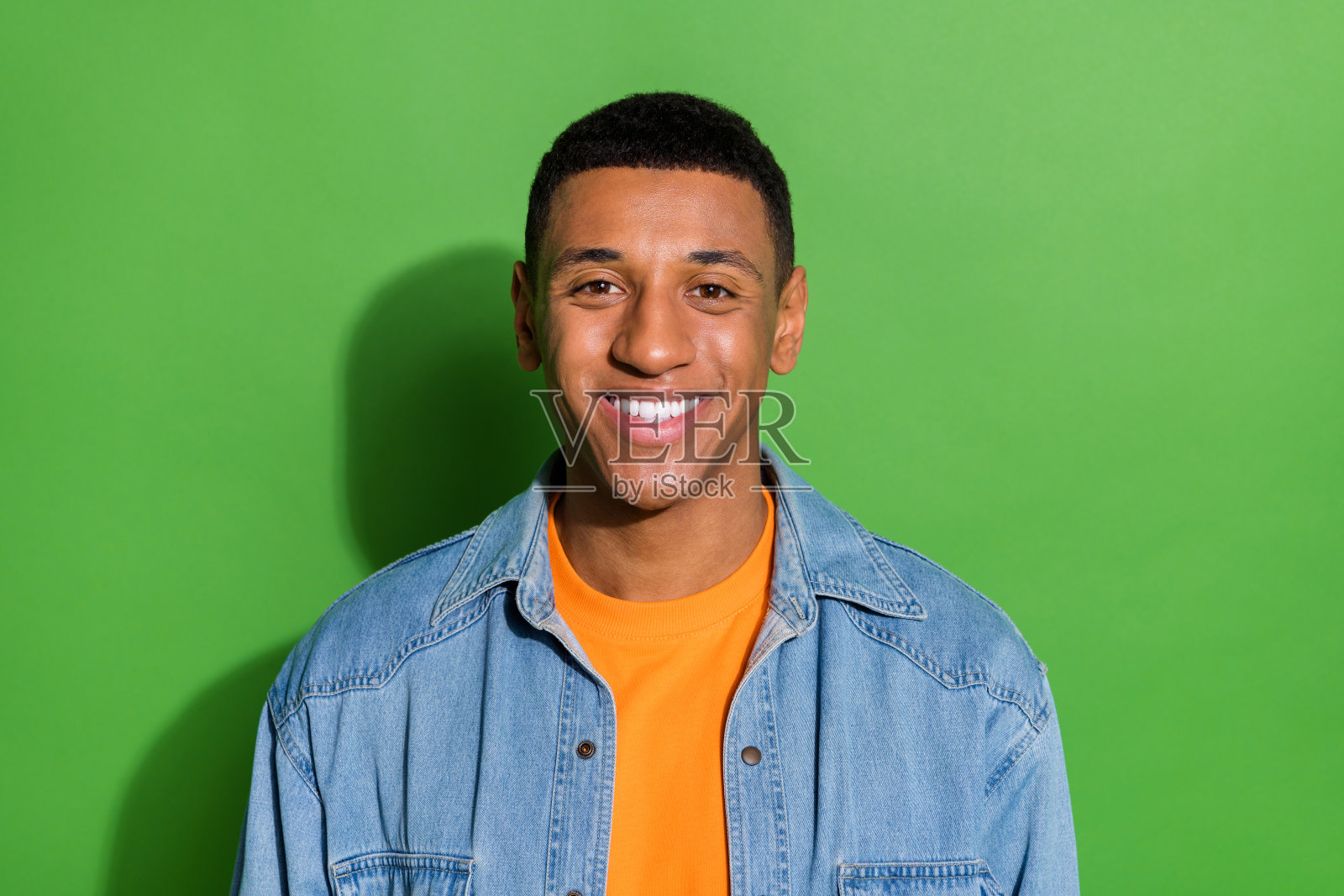 年轻帅气的男性穿着牛仔衬衫,前往牙科医生处照顾自己的健康,背景为绿色。照片摄影图片