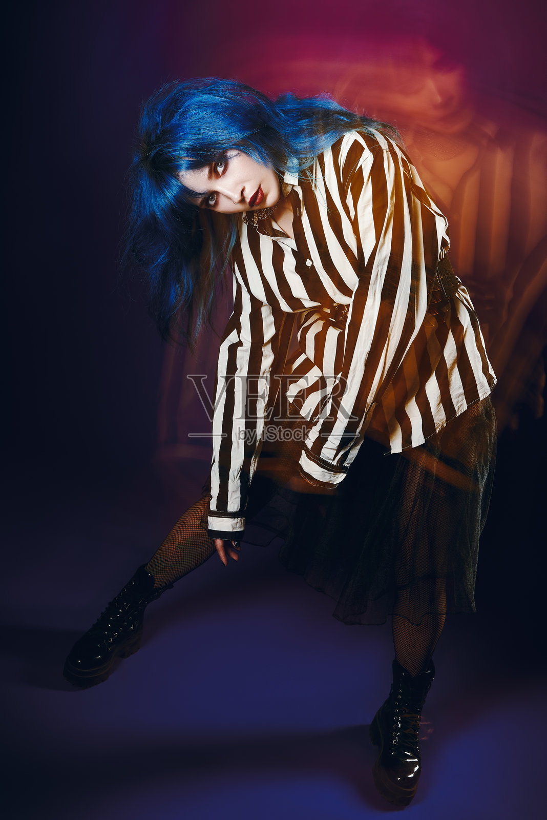 怪异的哥特女孩的工作室肖像。可爱的蓝发哥特女士穿着条纹衬衫和黑色裙子。照片摄影图片