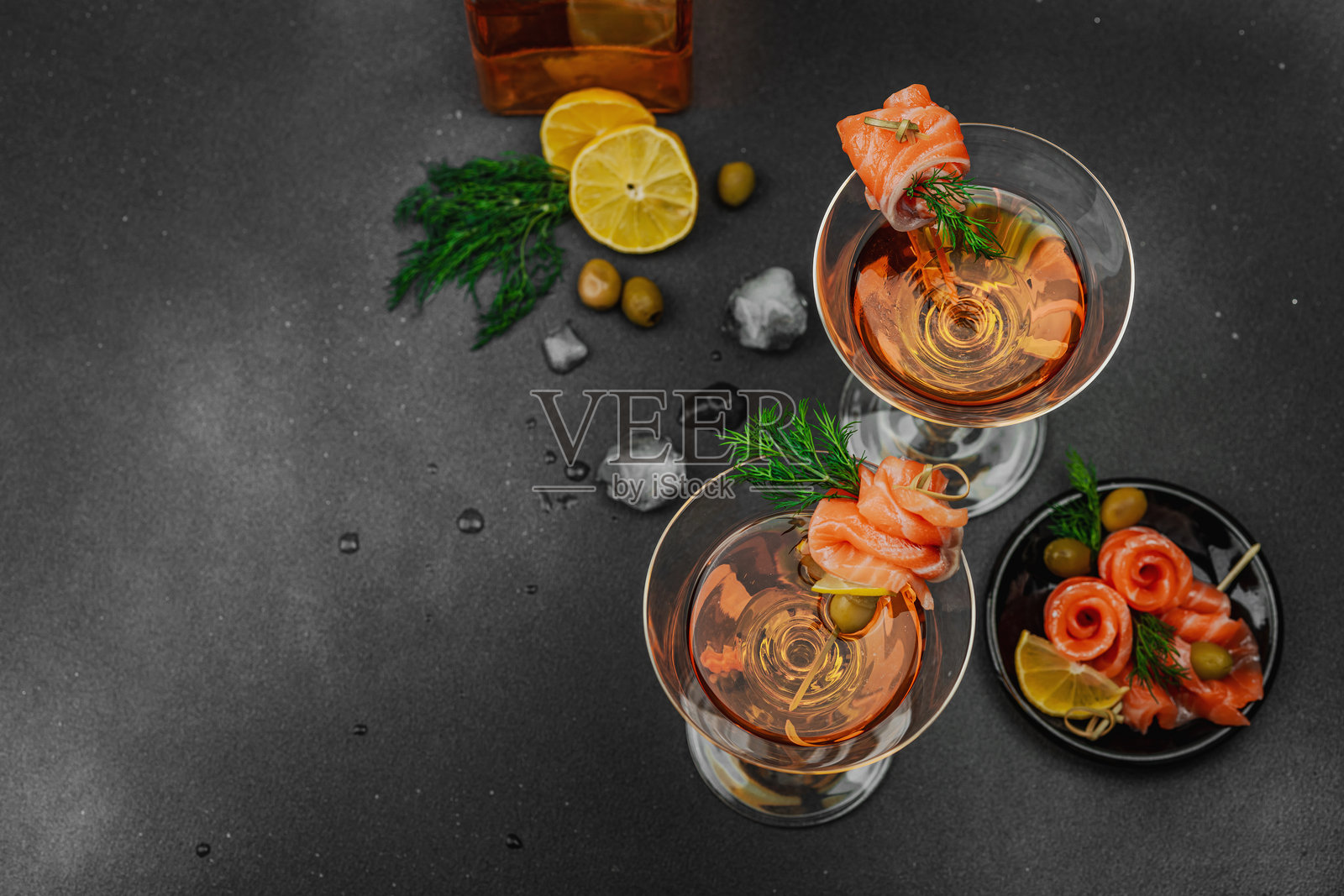 时尚的三文鱼马提尼鸡尾酒,配有熏三文鱼、橄榄、柠檬和莳萝。高端调酒艺术。照片摄影图片