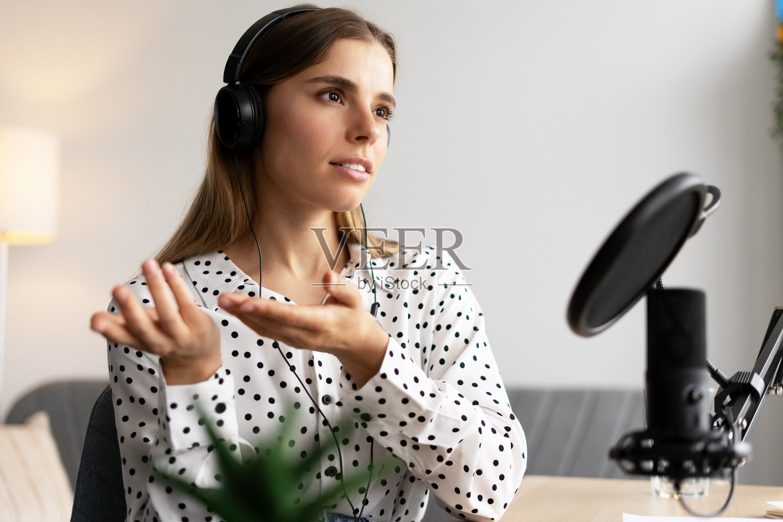 播客主持人戴着耳机,正在麦克风前录制在线音频内容照片摄影图片