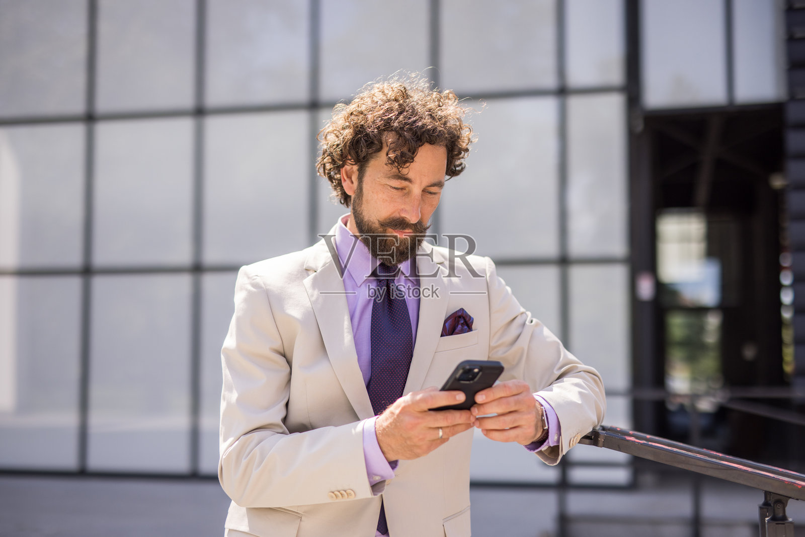 优雅的商人在现代办公大楼前使用智能手机照片摄影图片