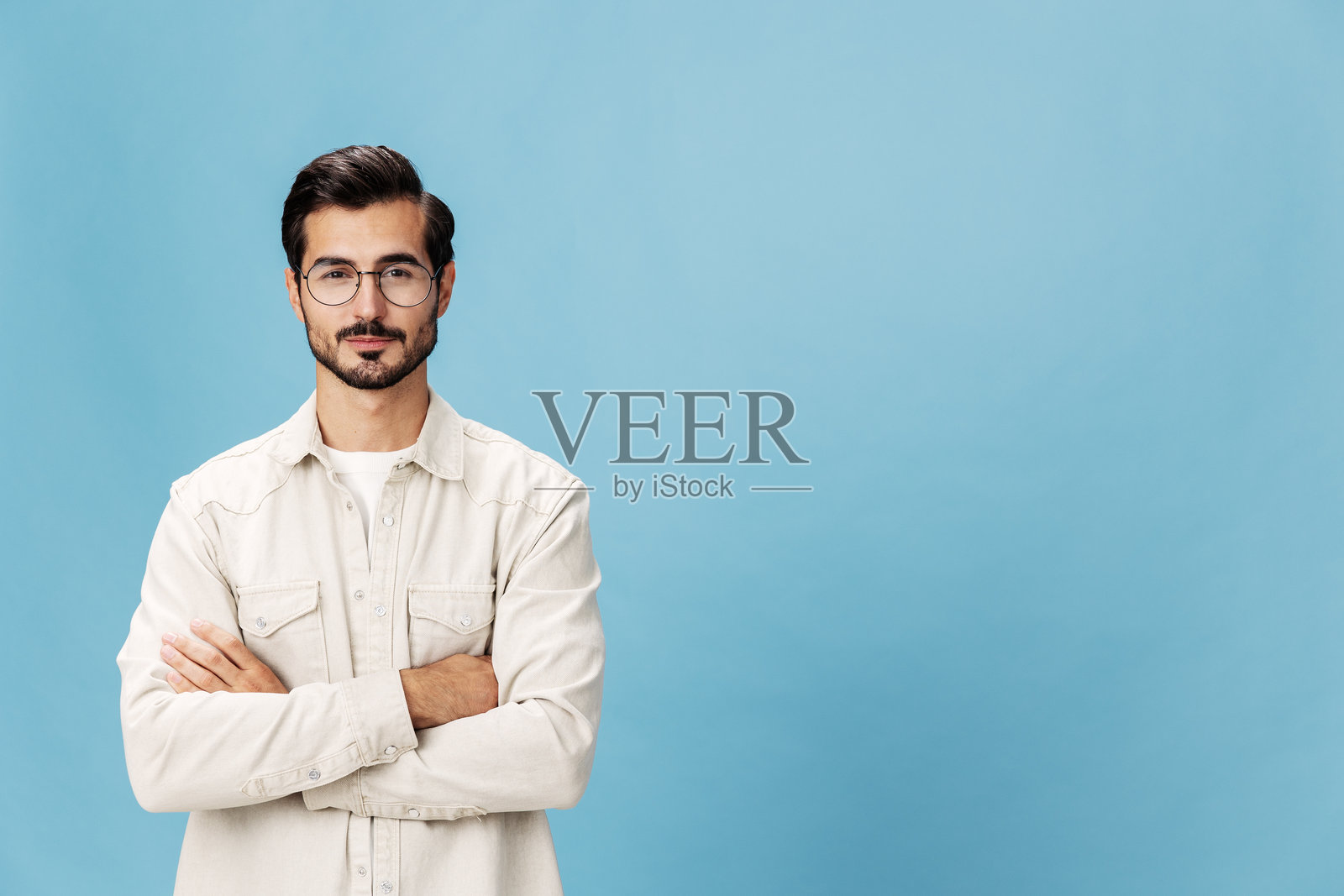 时尚男士微笑露齿,戴着近视和远视眼镜,背景为蓝色,穿着白色T恤,时尚服装风格,空间感十足。照片摄影图片