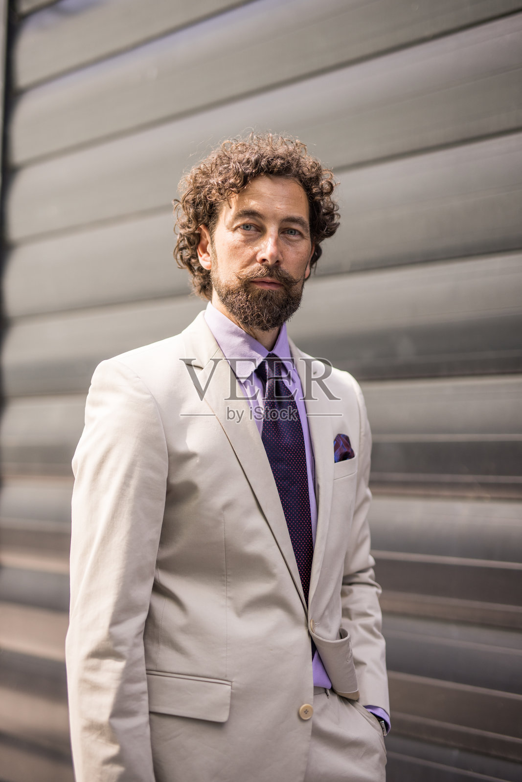 优雅的商人手插口袋在金属墙前摆姿势照片摄影图片