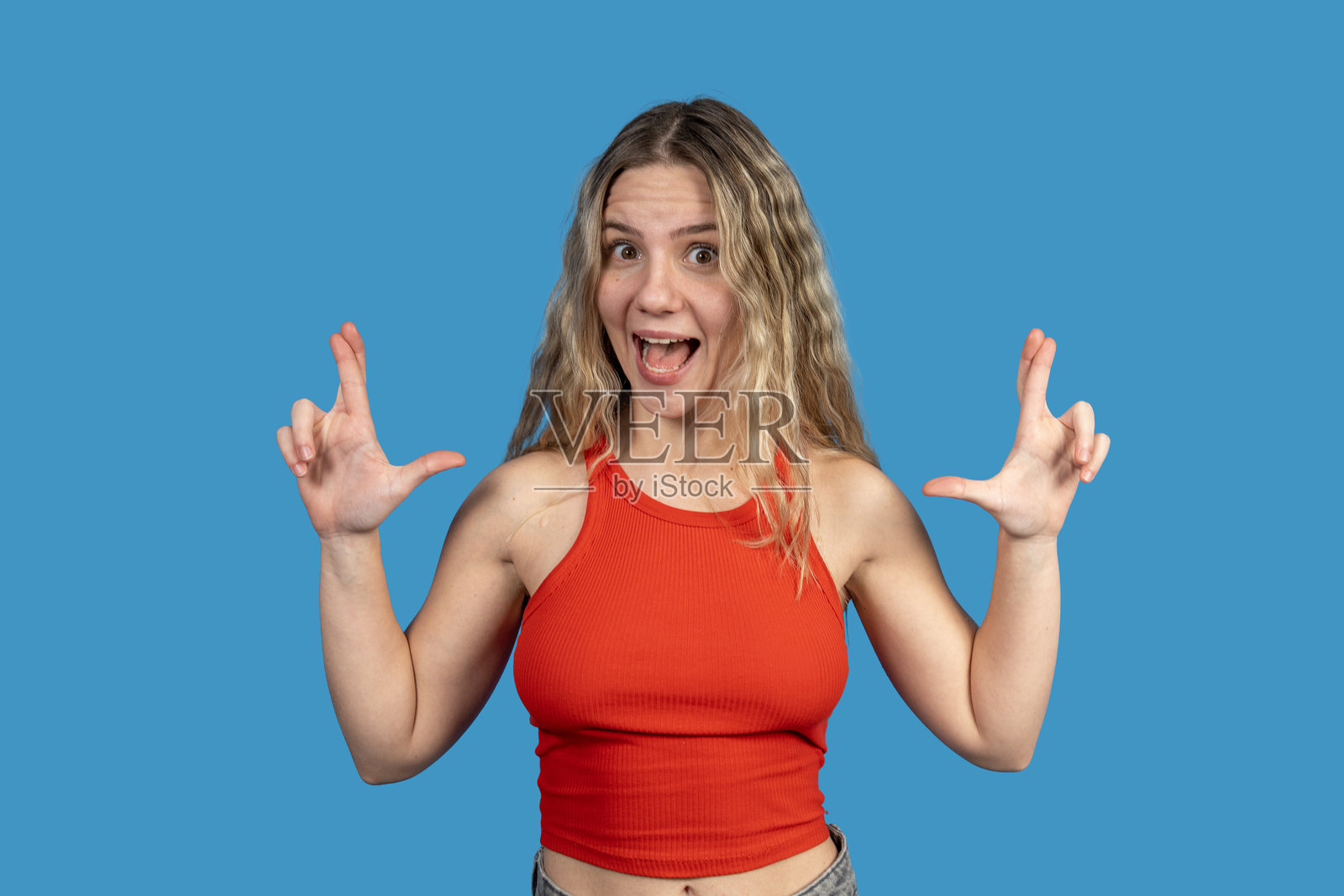 兴奋的年轻女性在蓝色背景下用手框住某物照片摄影图片