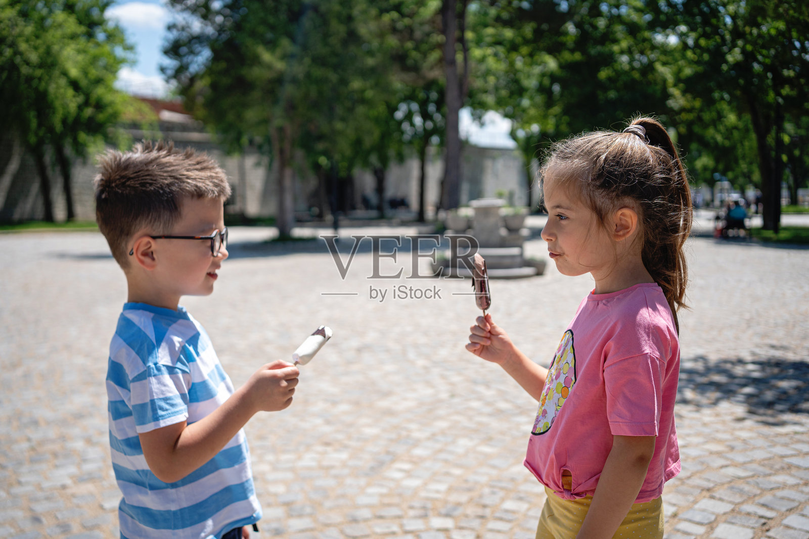 兄弟姐妹在阳光明媚的公园里一起享受冰淇淋照片摄影图片