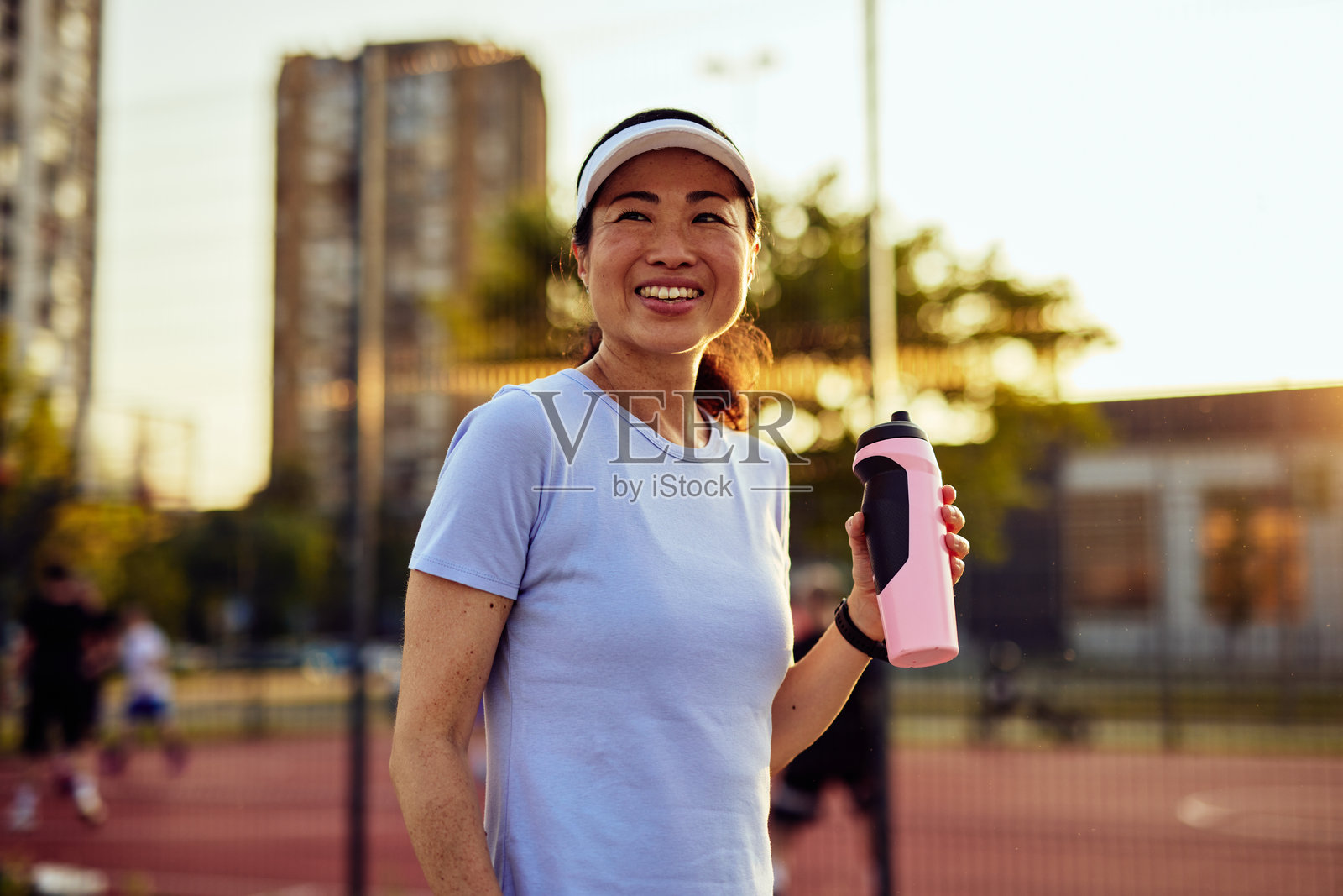 微笑的成熟亚洲女性在运动训练后喝水照片摄影图片