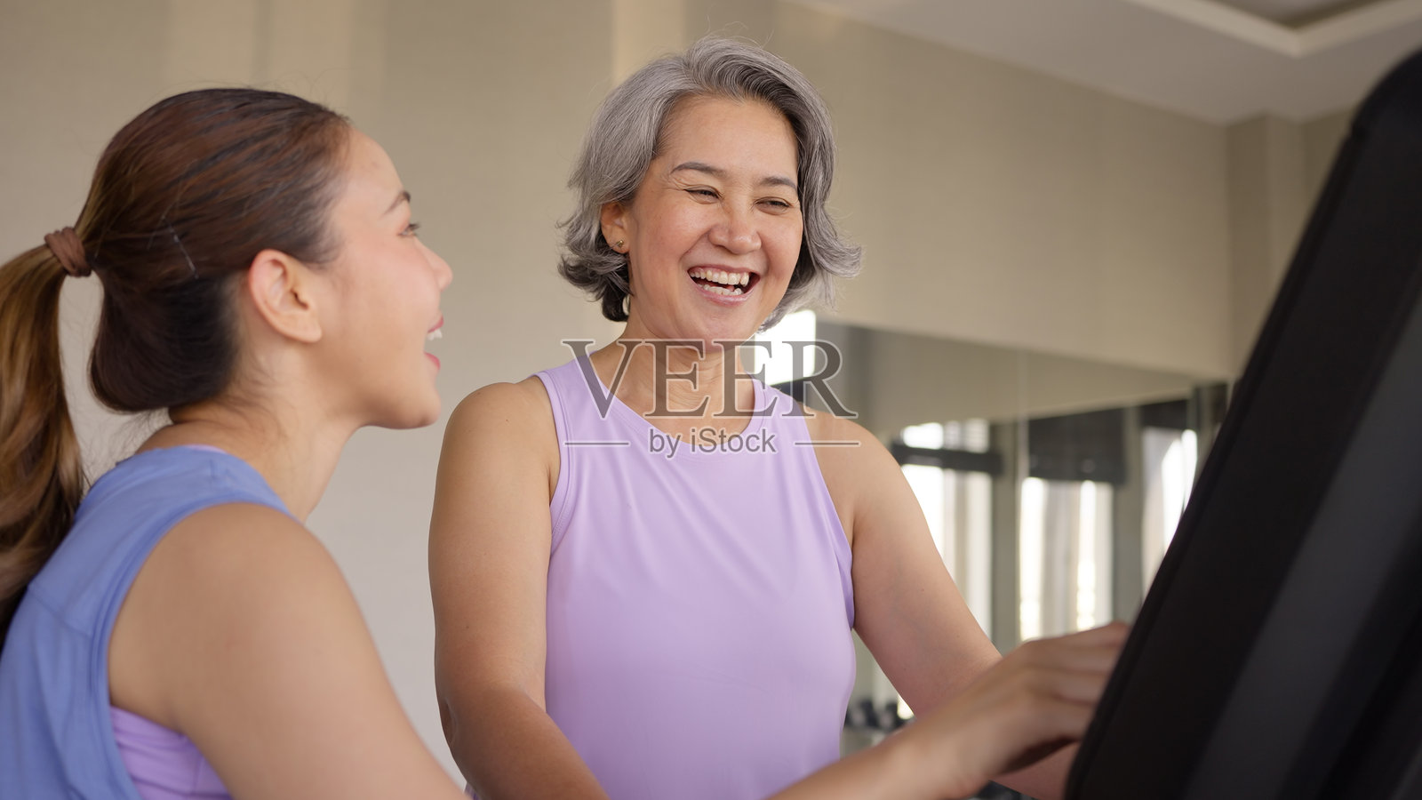 年轻活跃的成年人和成熟的中年母亲在健身房一起跑步锻炼,享受运动俱乐部的快乐,关注心理健康,保护老年人的生活平衡。照片摄影图片