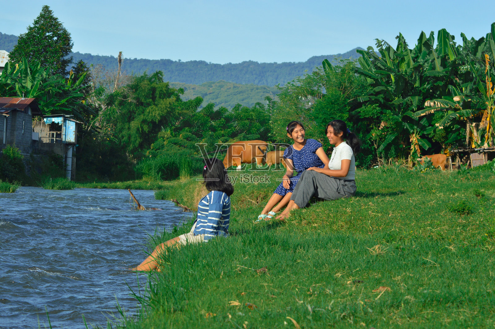 朋友们在河边的草地上欢笑聊天照片摄影图片