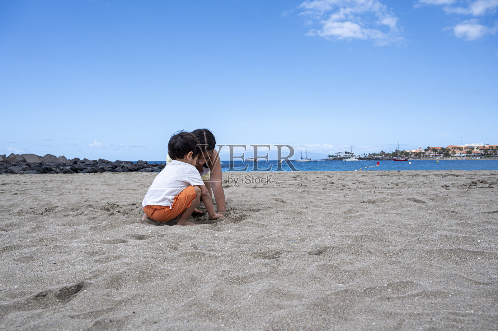 一个男孩和女孩在海滩上玩沙子。照片摄影图片