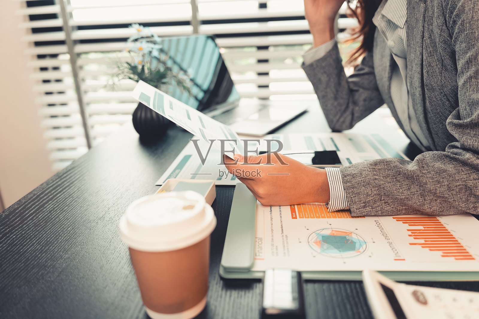 专业女性正在用计算器和笔记本电脑检查图表和财务数据,并进行分析和审查。年轻女性在桌子上处理纸质文件的特写镜头。照片摄影图片