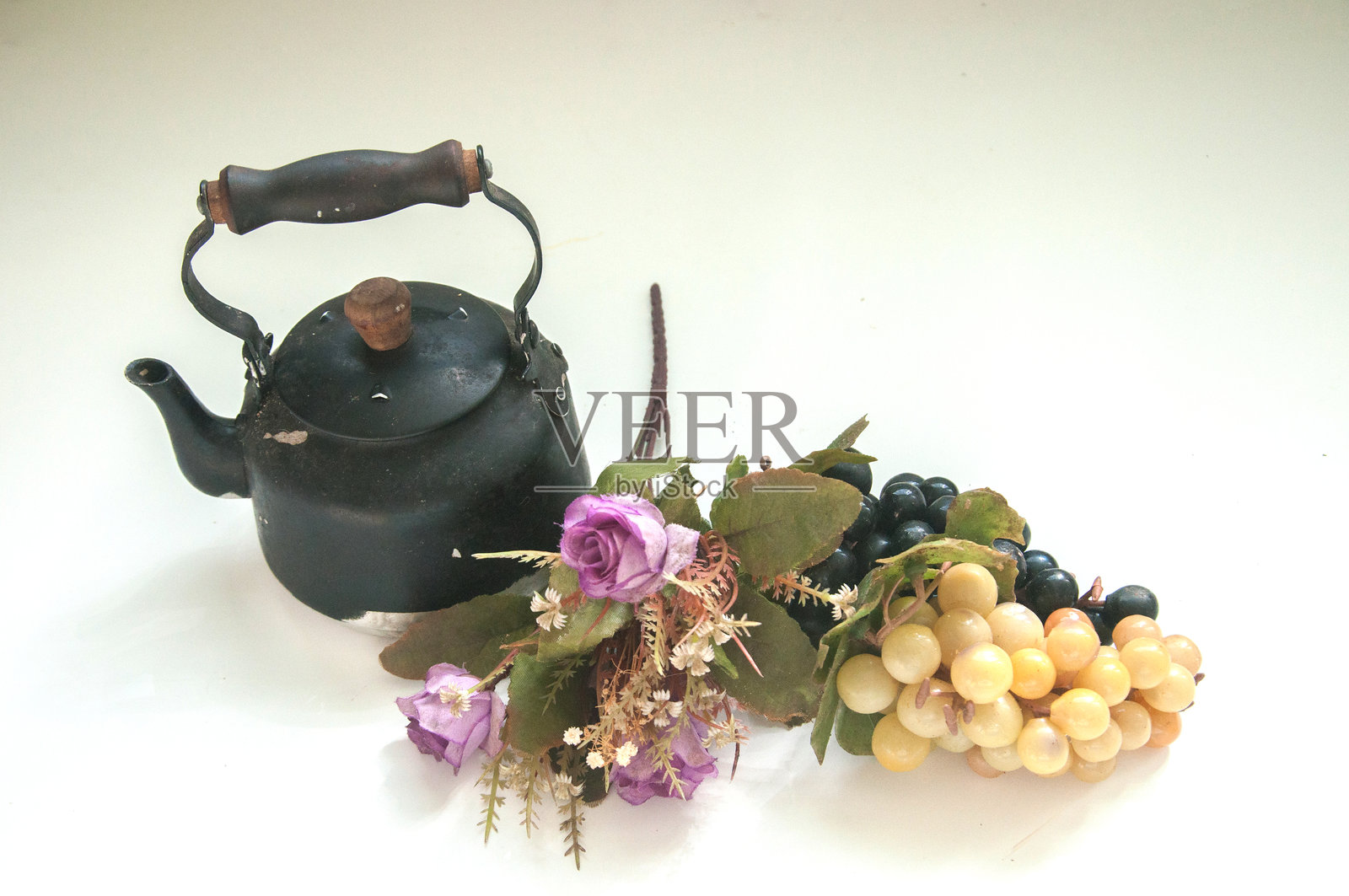 桌子上的茶壶、紫色花朵和葡萄照片摄影图片