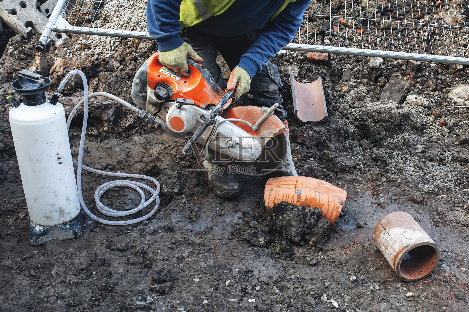 建筑工人在工地上用电锯和金刚石刀片切割粘土排水管照片摄影图片