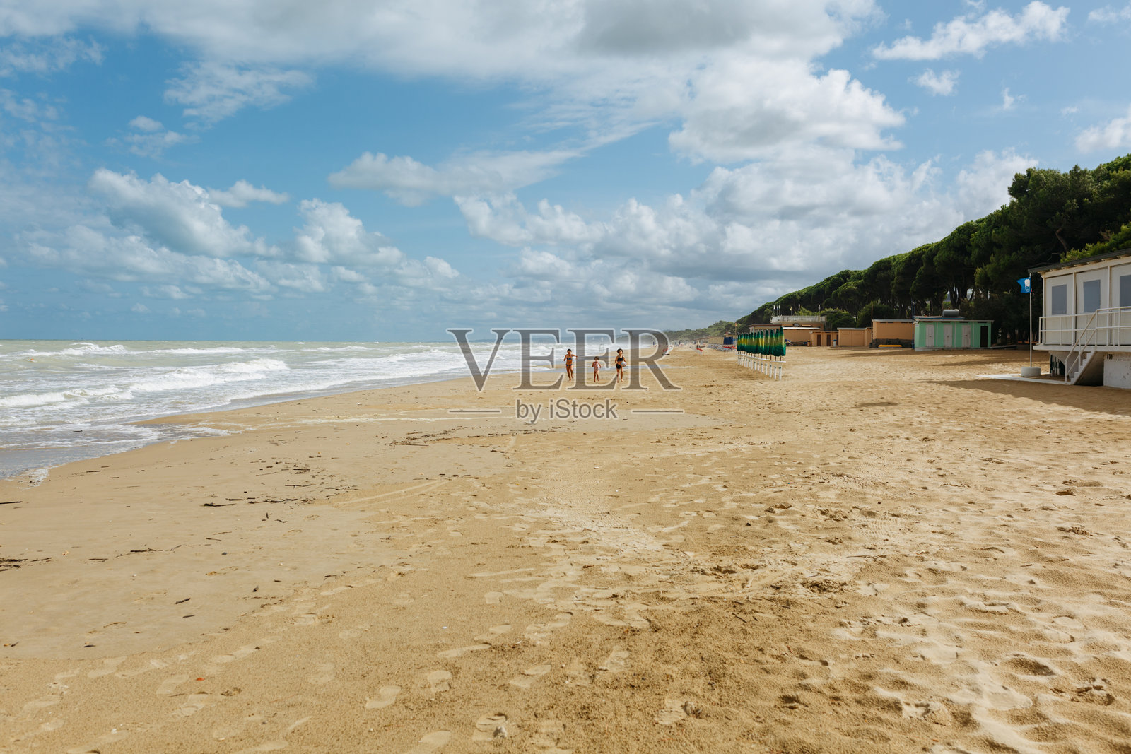 阳光明媚的日子里,三个孩子在海滩上奔跑的广角视图照片摄影图片