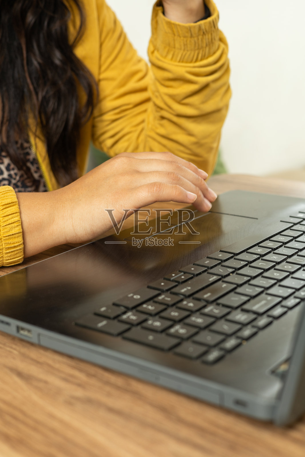 穿着黄色夹克的女孩在办公室里用笔记本电脑打字照片摄影图片