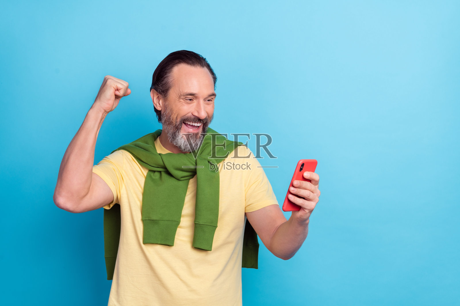 高兴的帅气男人举起拳头庆祝,背景为蓝色。照片摄影图片