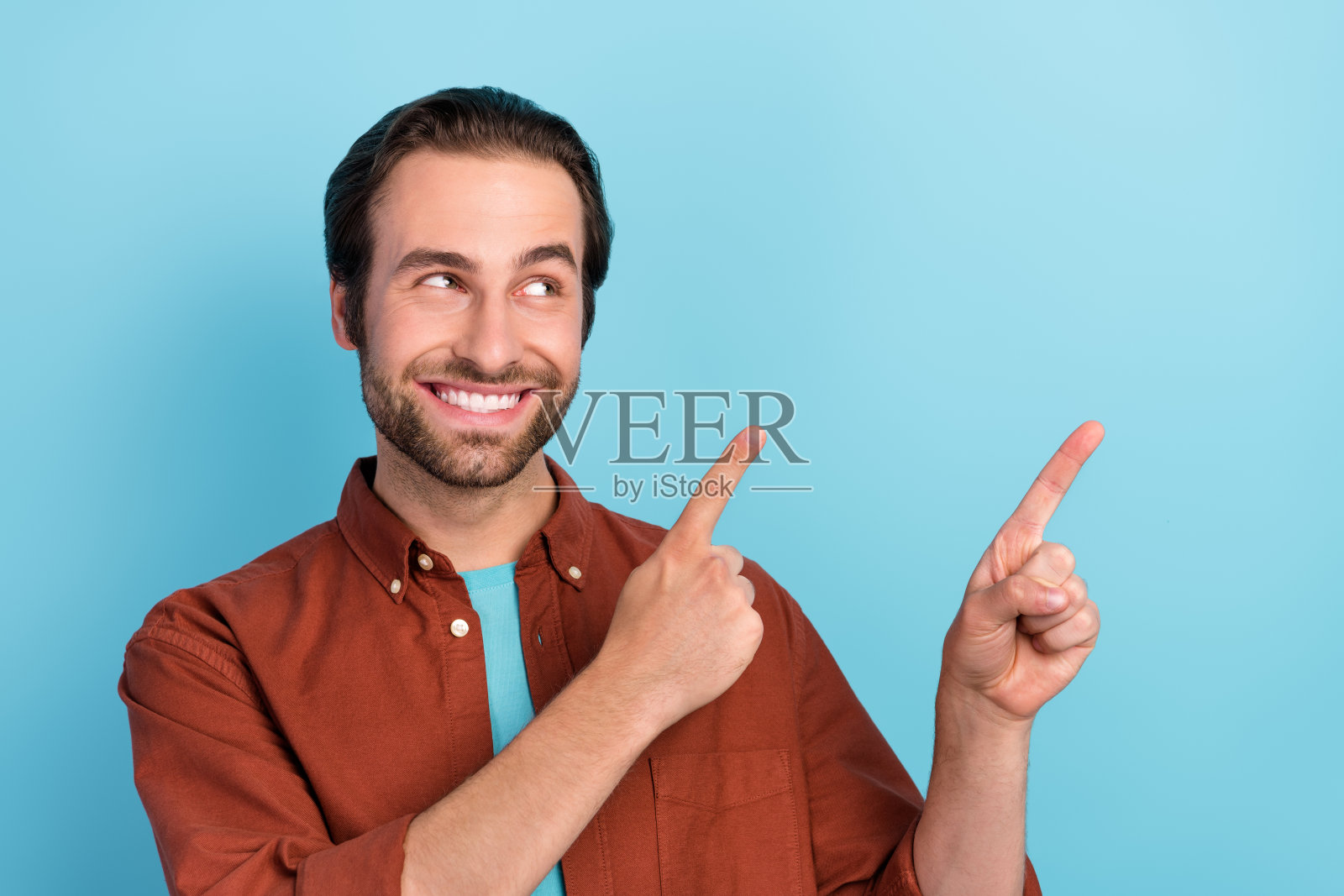 梦幻般的迷人男性在蓝色背景上看向空白处,适合广告选项或产品推广。照片摄影图片