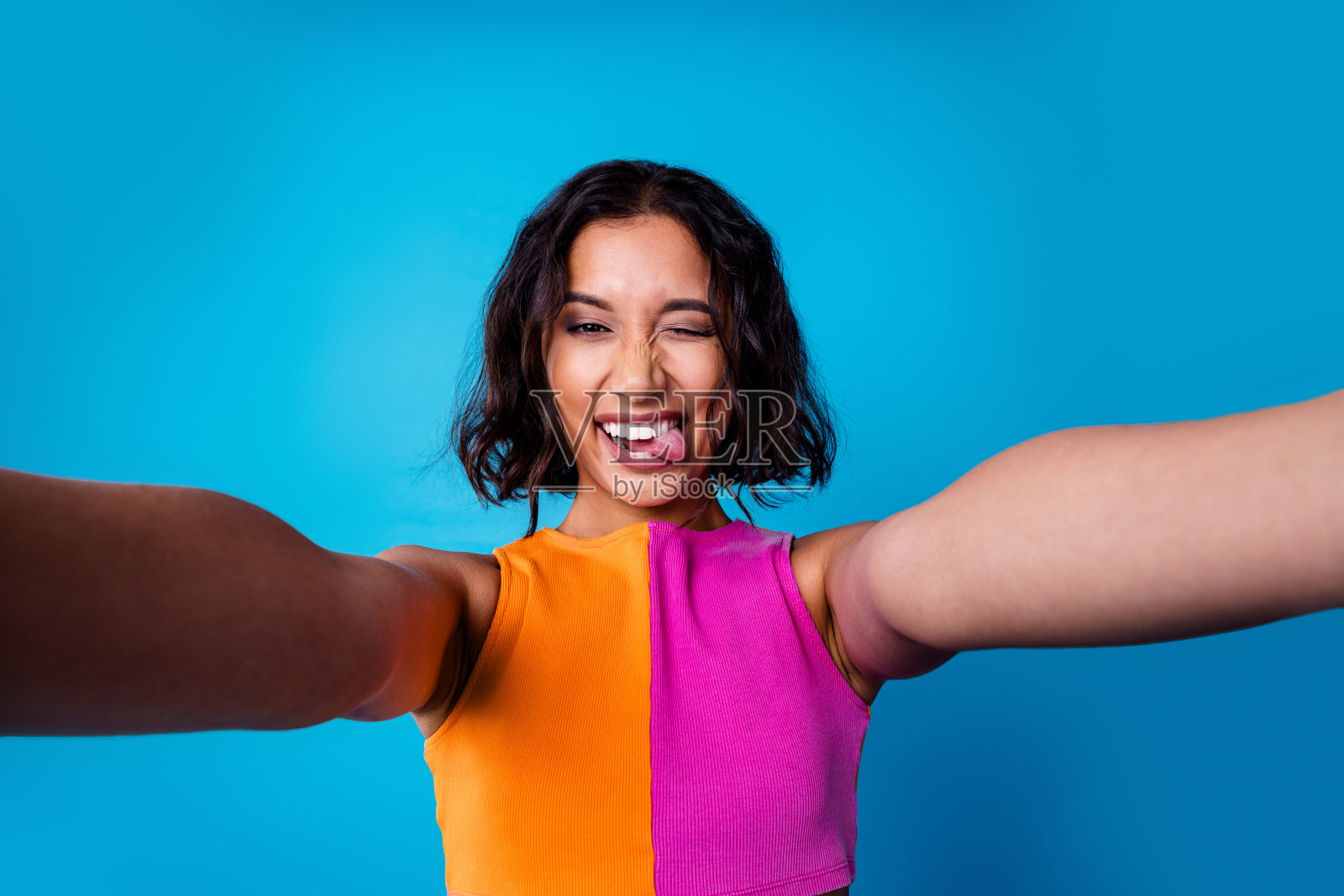 穿着时尚多彩服装的快乐年轻女性在鲜艳的蓝色背景前自拍照片摄影图片
