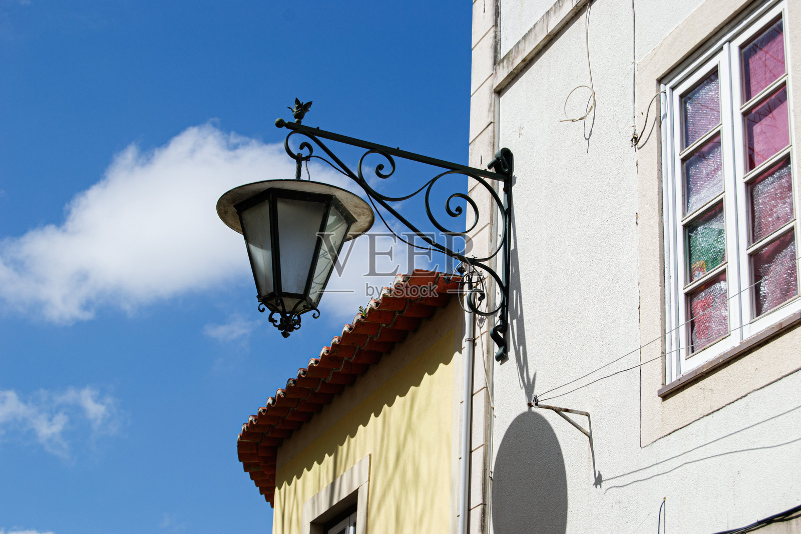 葡萄牙卡尔达斯达雷尼亚建筑外立面上的复古灯具,映衬着蓝天照片摄影图片