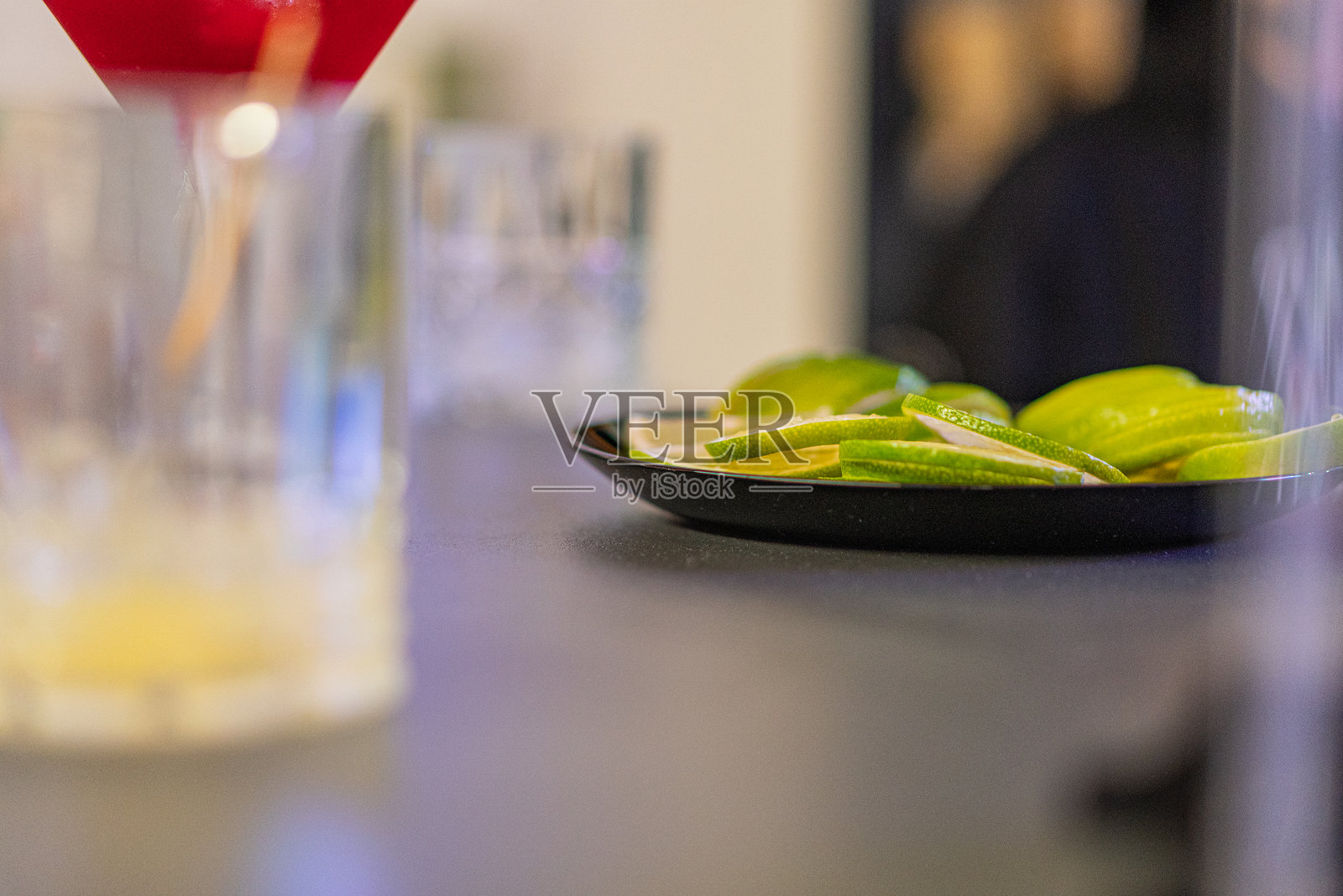 图像展示了一个充满活力、令人垂涎的酒吧或餐厅场景,重点是两碗新鲜的青柠和一个水壶。青柠传达出新鲜感,可能用于调味饮品。照片摄影图片