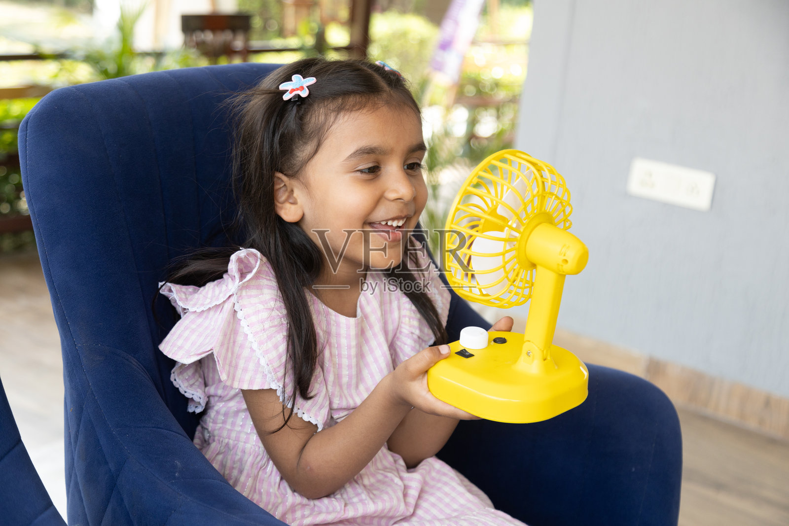 快乐的印度小孩在家中用电风扇降温,享受夏季的清凉。摆脱炎热天气的舒适感。童年。照片摄影图片