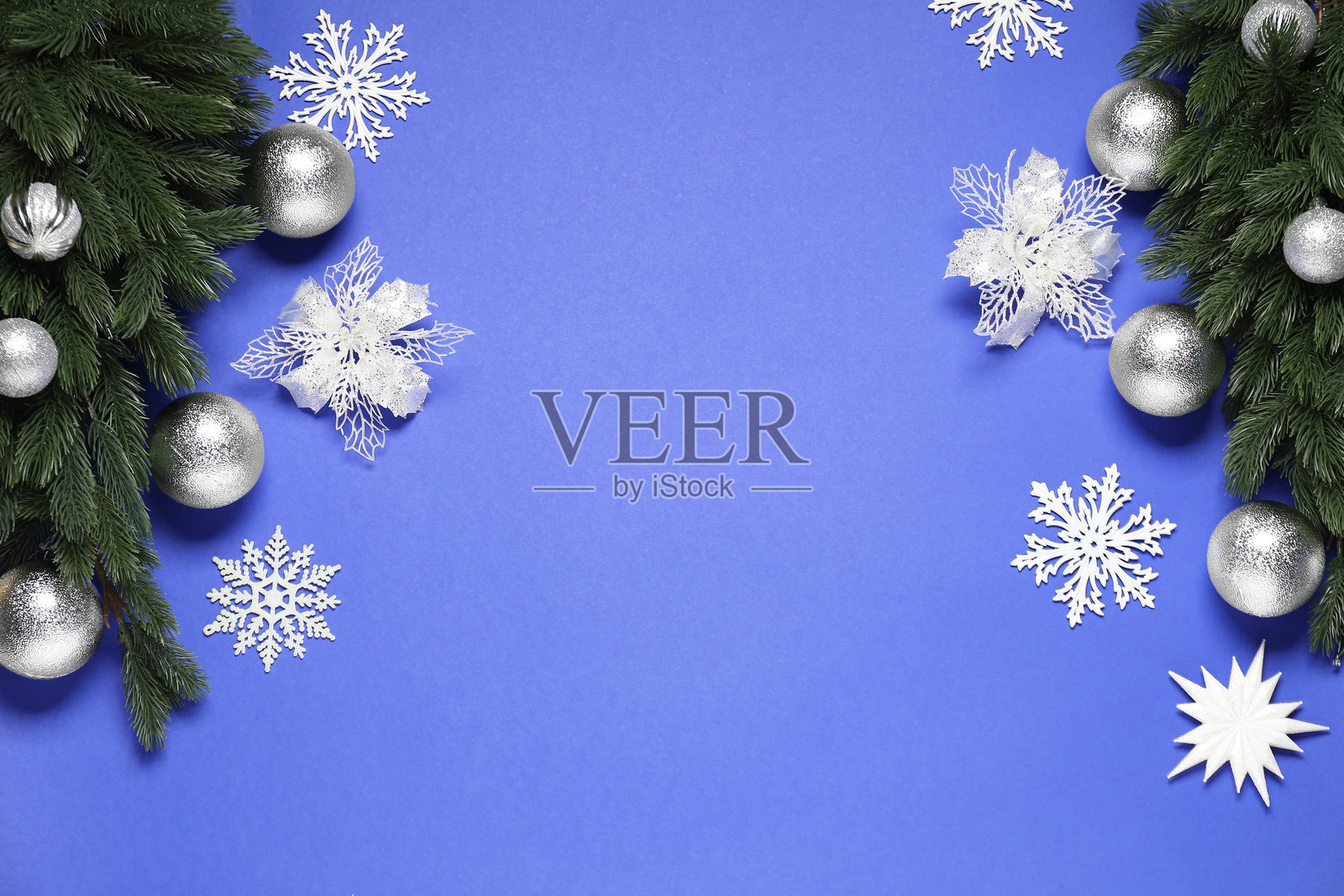 蓝色背景上的冷杉树枝、圣诞球和装饰性雪花,平铺展示。留有文本空间。照片摄影图片