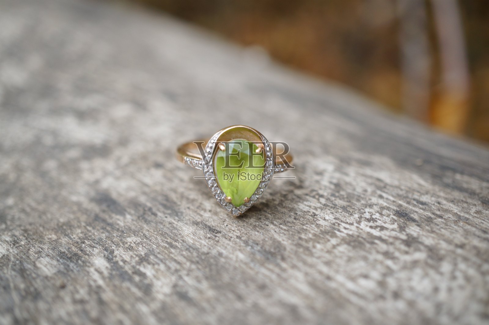 一枚镶有橄榄石的珍贵戒指,背景为木质纹理。照片摄影图片