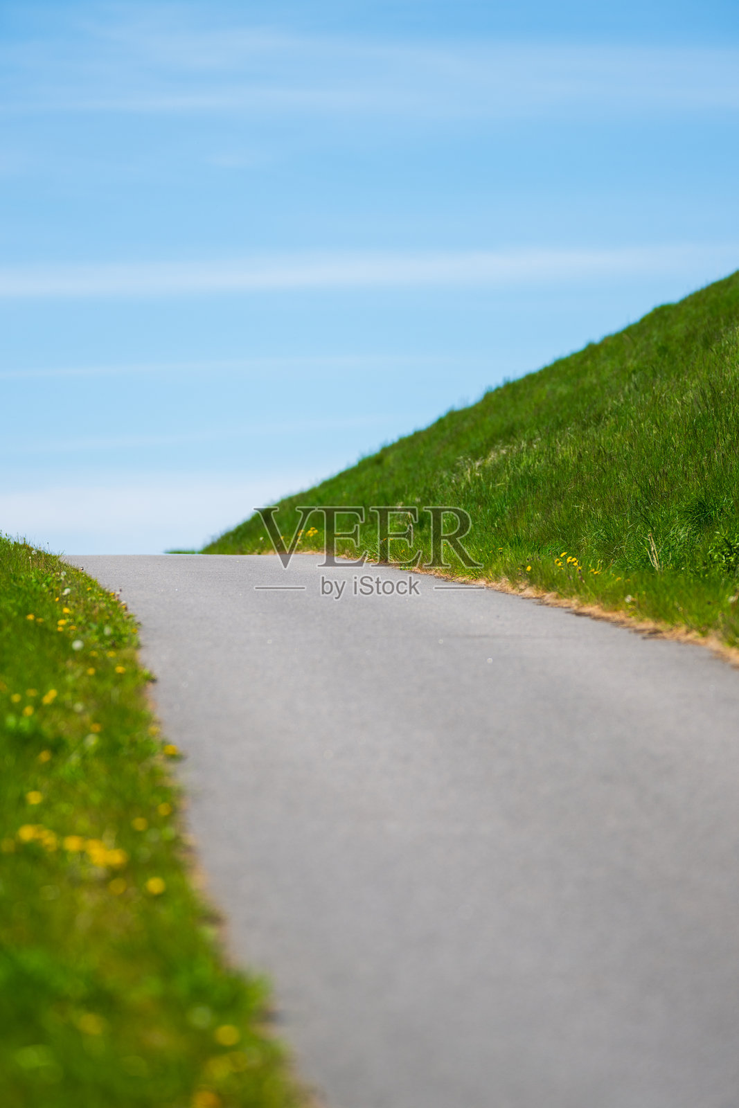 沥青公路蜿蜒穿过草坡。照片摄影图片
