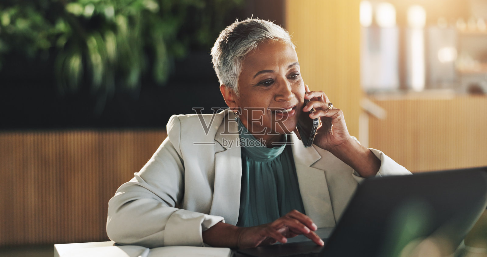 办公室中,女性与笔记本电脑进行电话会议,讨论日程更新和财务报告。成熟人士,使用手机获取提案反馈、投资报价和谈判信息。照片摄影图片