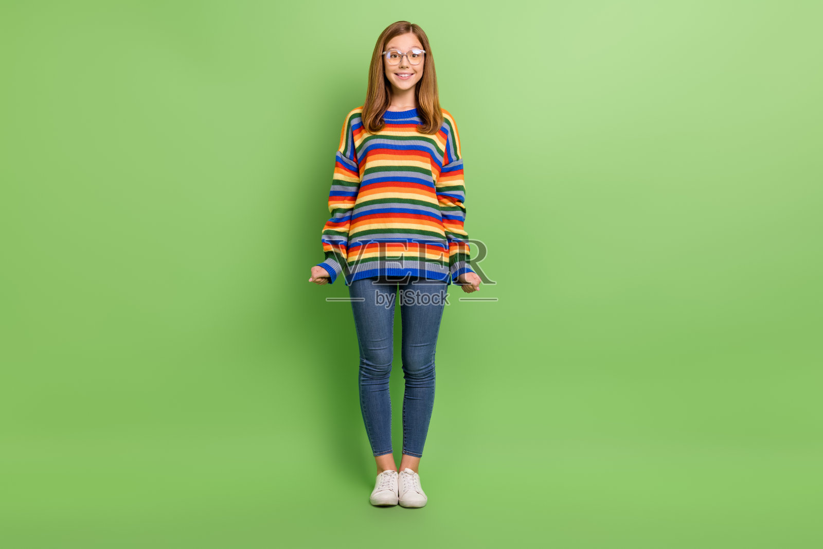 全身身材的迷人、快乐、有趣的女孩在明亮的绿色背景上摆姿势。照片摄影图片