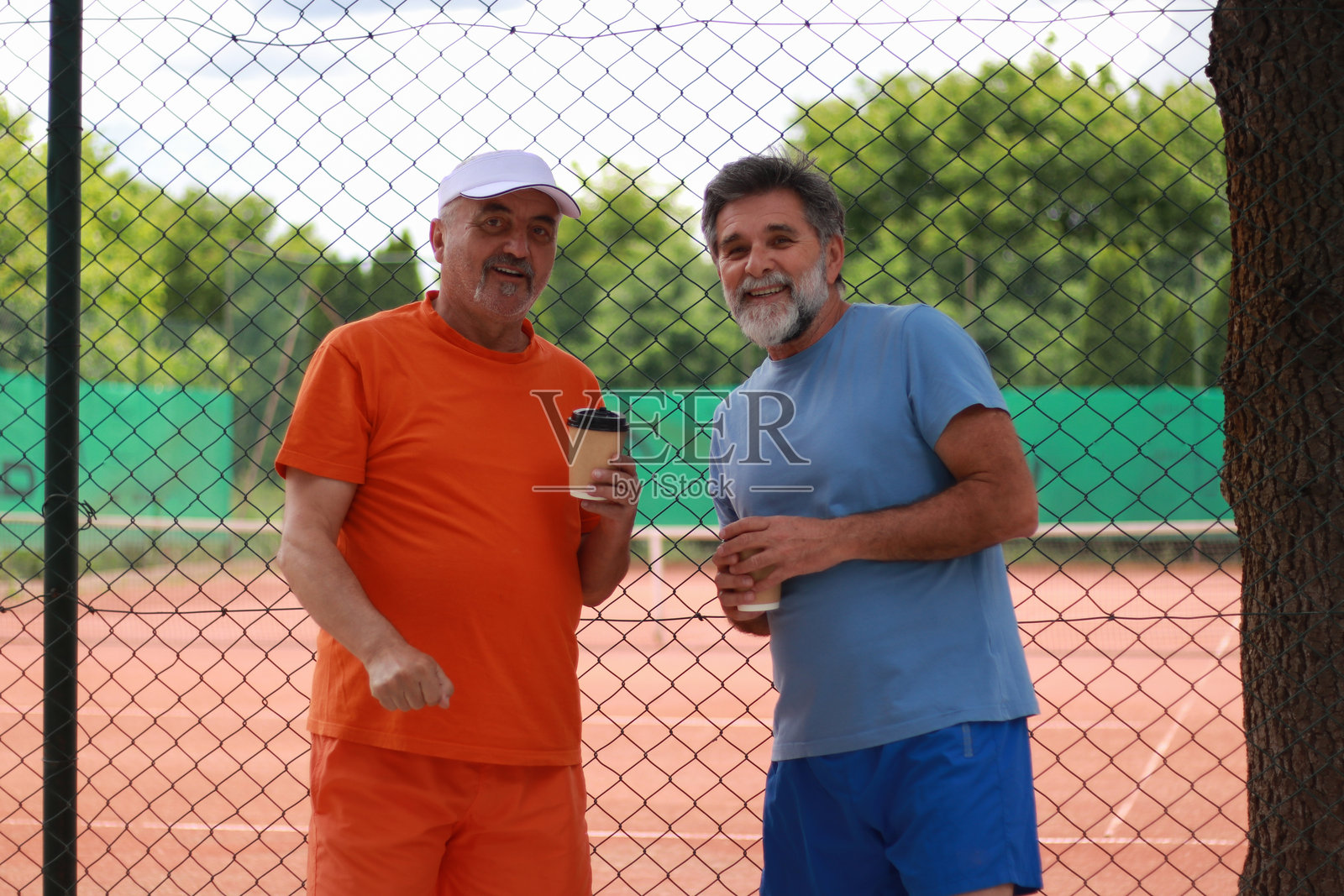 两位老年男性在训练前享受咖啡和交谈。照片摄影图片