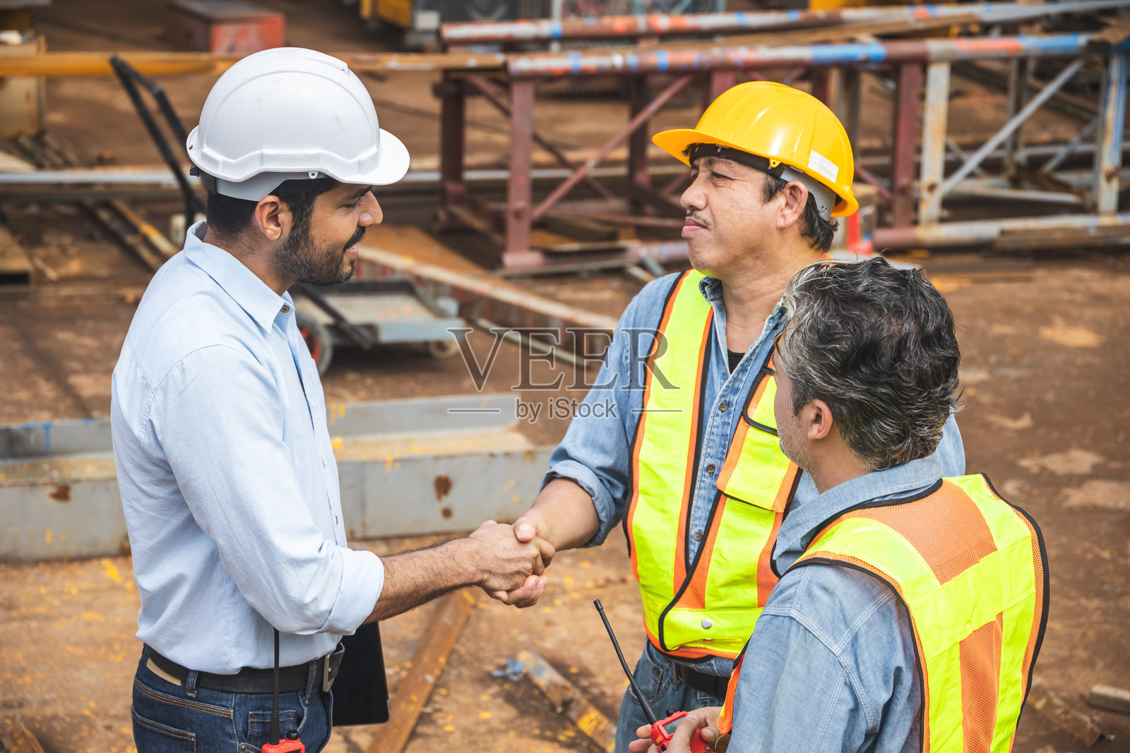 工人团队与承包商在建筑工地握手达成协议,工程师项目联系。照片摄影图片