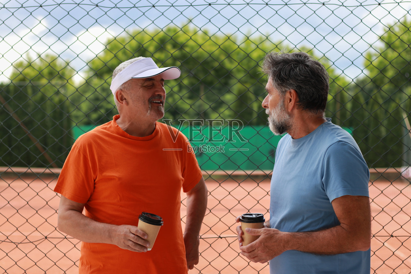 两位老年男性在训练前享受咖啡和交谈。照片摄影图片