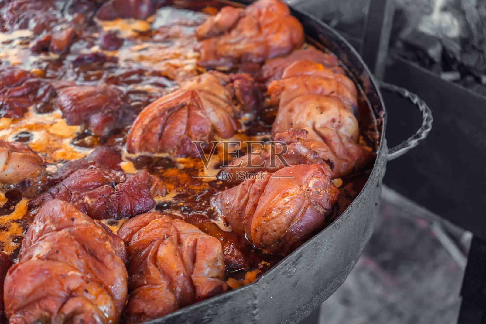 美味的烤猪蹄,经典的德国或捷克菜肴,在大平底锅中烹饪。街头集市上受欢迎的舒适食品。诱人的猪蹄。传统的户外烹饪概念。照片摄影图片