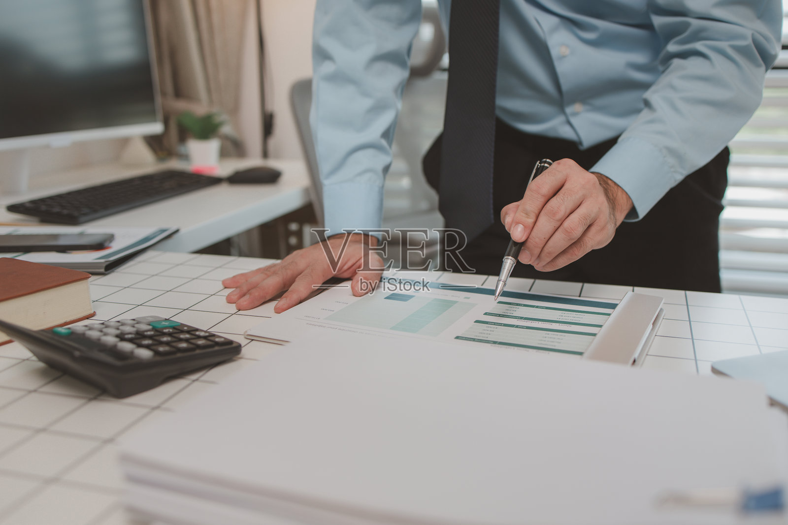 首席会计师正在努力检查文件和财务数据,以确保与支出报告一致,一位商人在他的私人办公室里进行计算。照片摄影图片