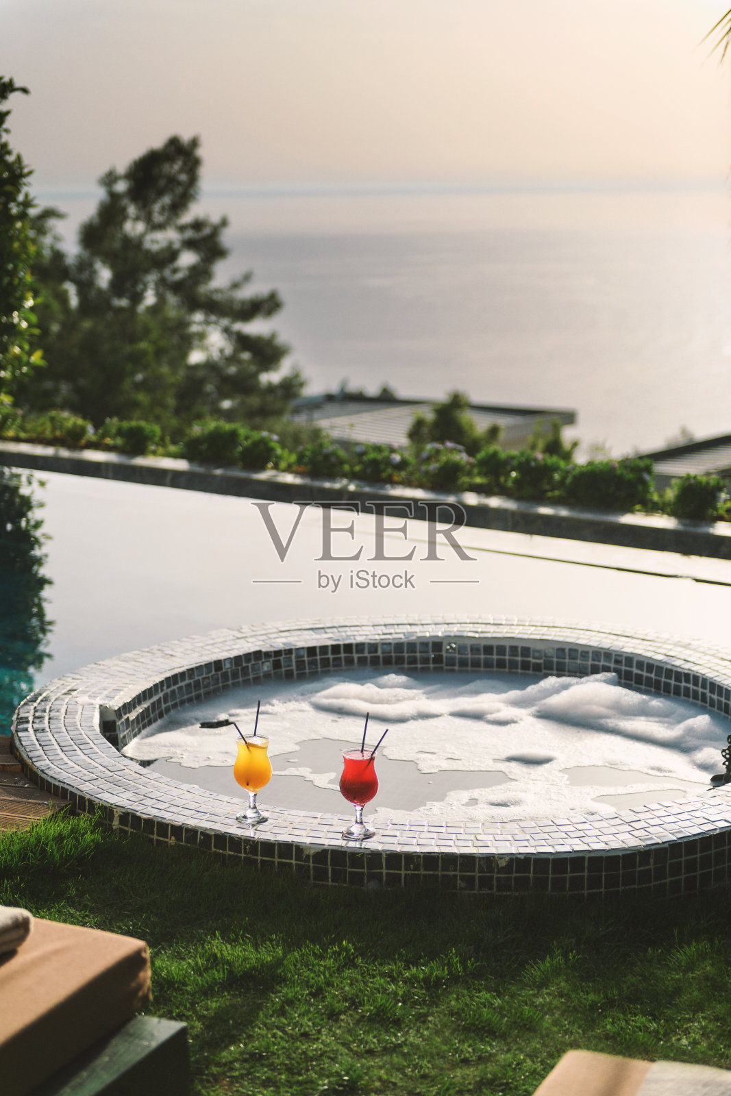 泳池边酒店房间里的五彩鸡尾酒与泡泡按摩浴缸照片摄影图片