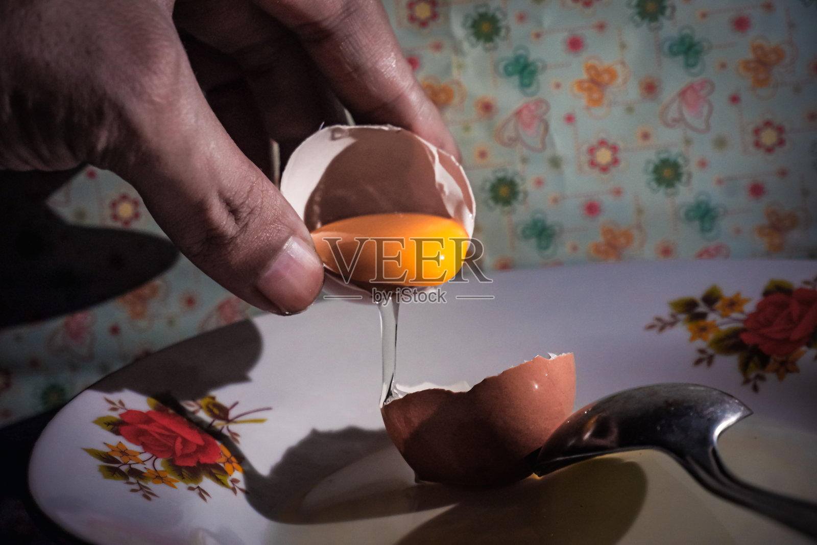 在花卉盘上敲蛋,蛋黄滴落照片摄影图片