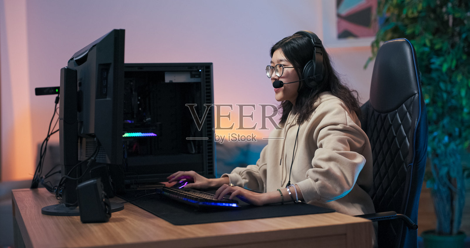 女孩在电脑上玩游戏。职业玩家赢得了网络锦标赛,女人高兴地举起双手,转动旋转椅,兴奋地尖叫,戴上耳机听音乐并唱歌。照片摄影图片