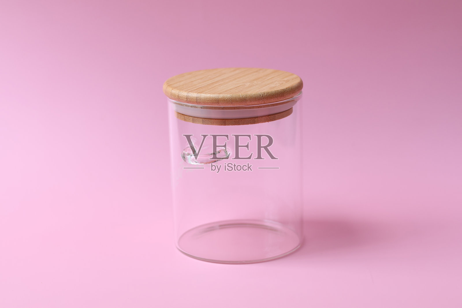 粉色背景上的空玻璃罐,带盖,适用于食品。侧视图照片摄影图片
