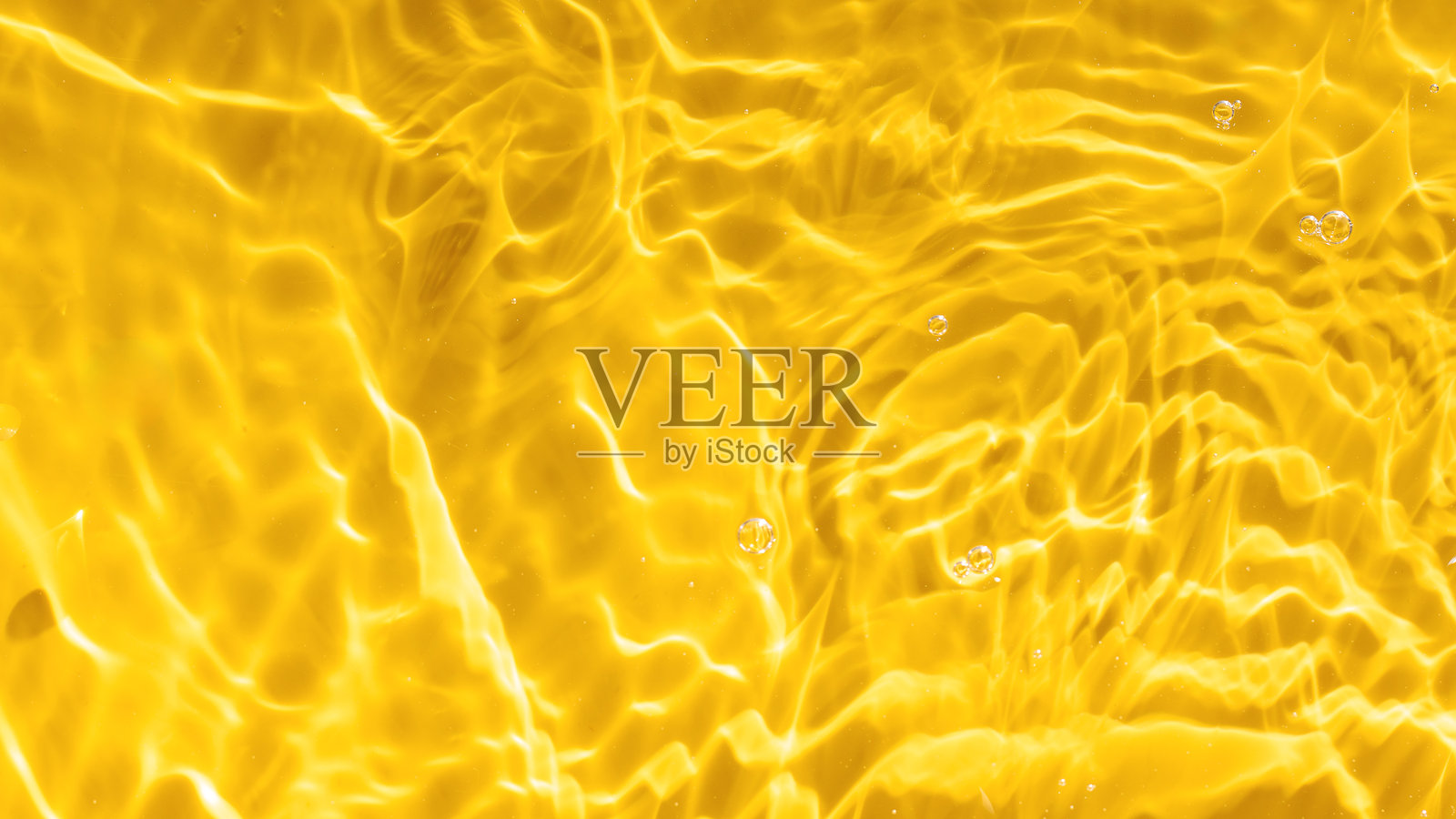 阳光下波纹荡漾的黄色水面抽象背景。俯视图,留白空间。照片摄影图片