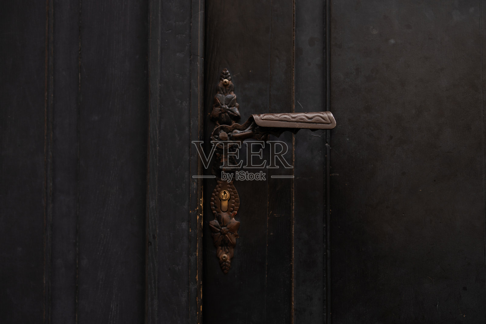 古董青铜门把手装饰在深色木门上照片摄影图片