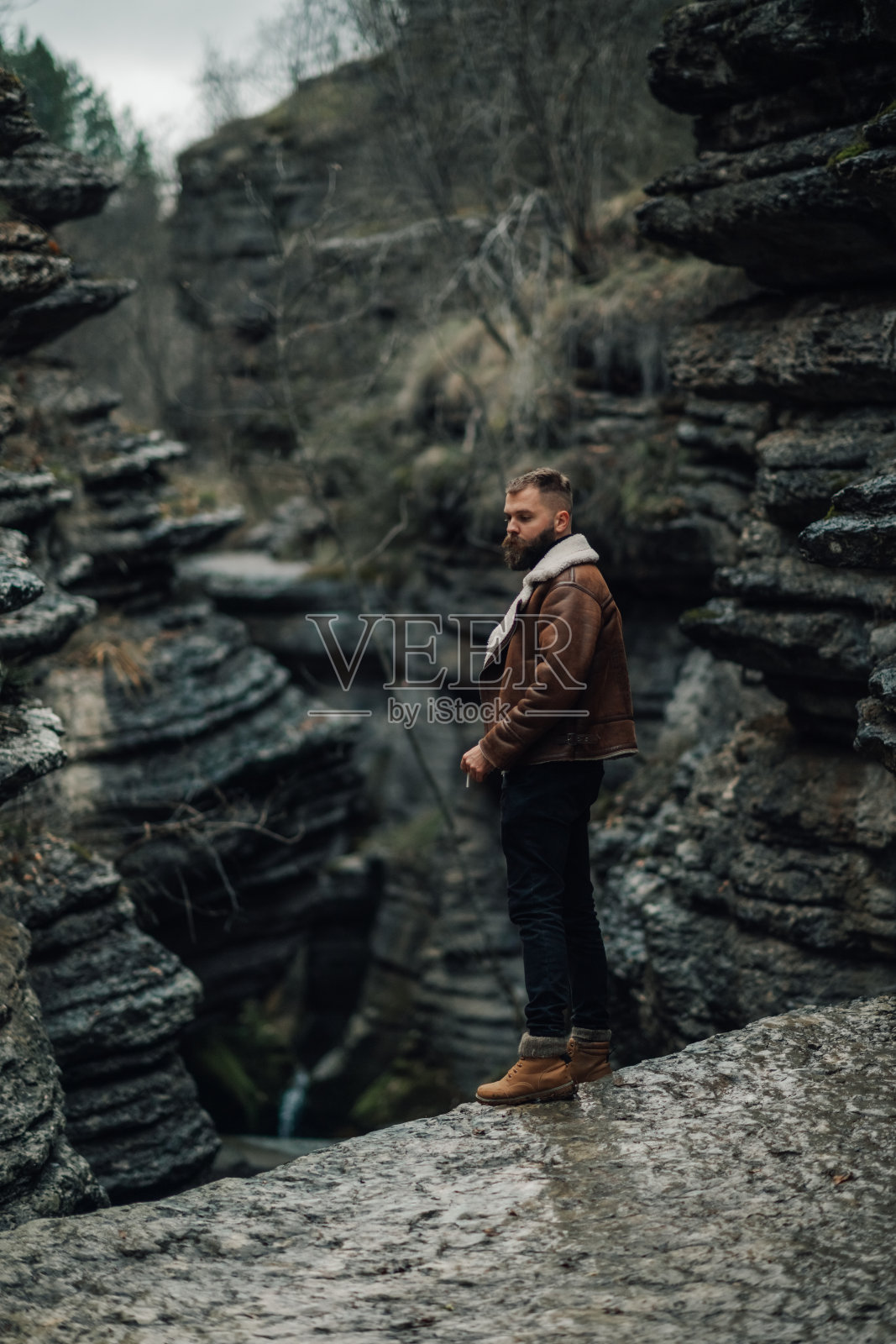 年轻男子在岩石峡谷中探险,旁边有瀑布照片摄影图片