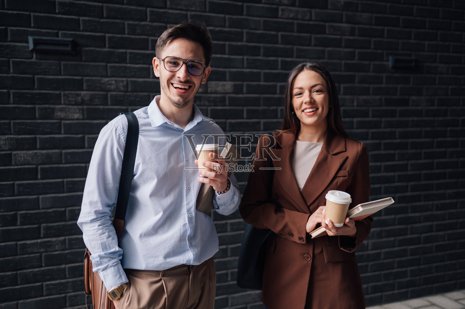 微笑的商务同事们手持一次性咖啡杯和书籍照片摄影图片