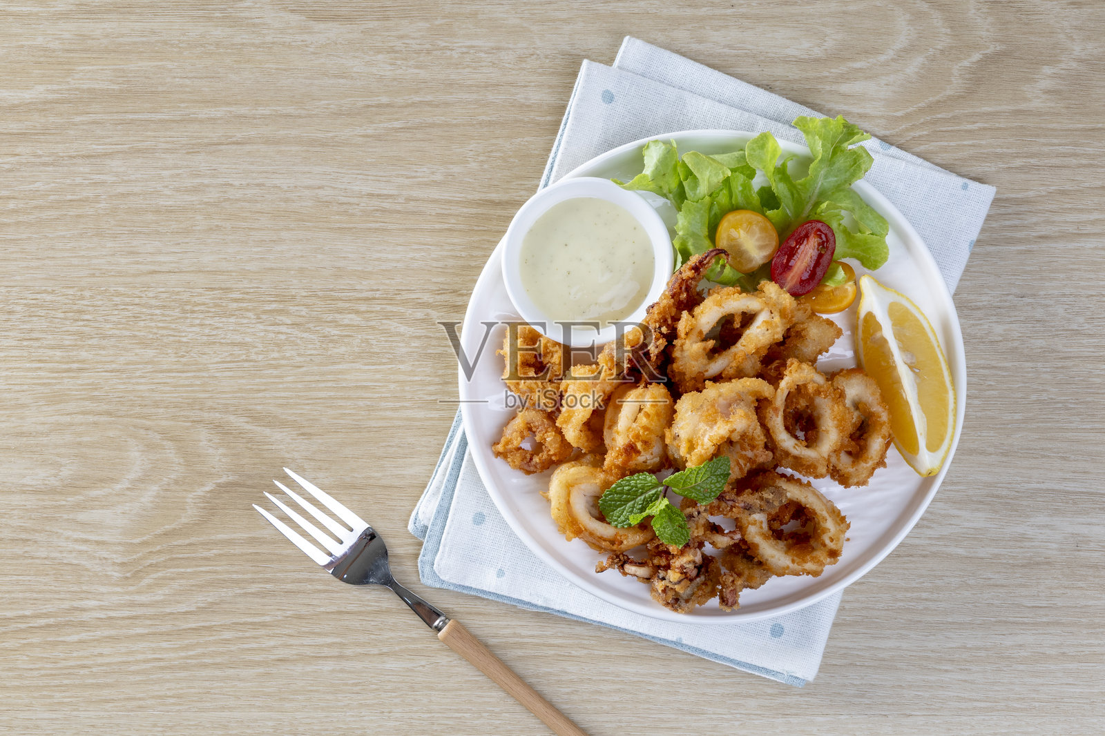 炸鱿鱼:嫩滑的鱿鱼圈裹上调味面糊,油炸至酥脆完美,配以马里纳拉酱或蒜味蛋黄酱供蘸食。照片摄影图片