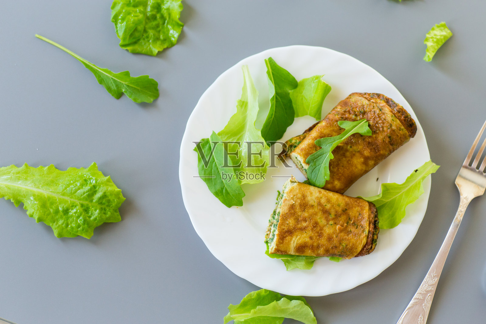 健康的蛋卷配绿叶菜,摆放在白色盘子上照片摄影图片