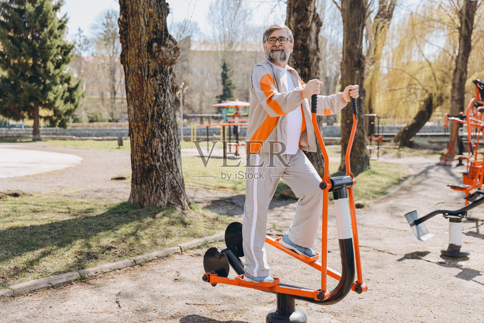 老年男子在户外健身房使用椭圆机锻炼照片摄影图片